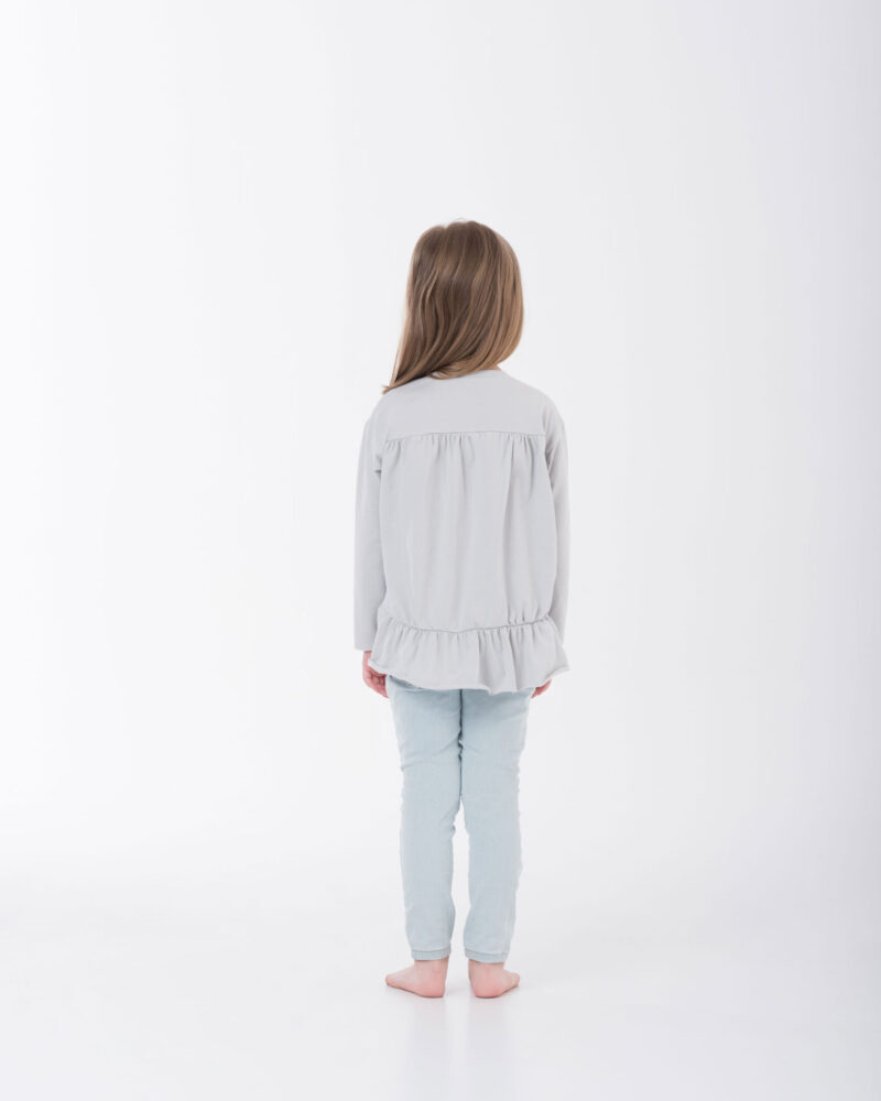 dziewczynka w falbankowej bluzce stojąca tyłem