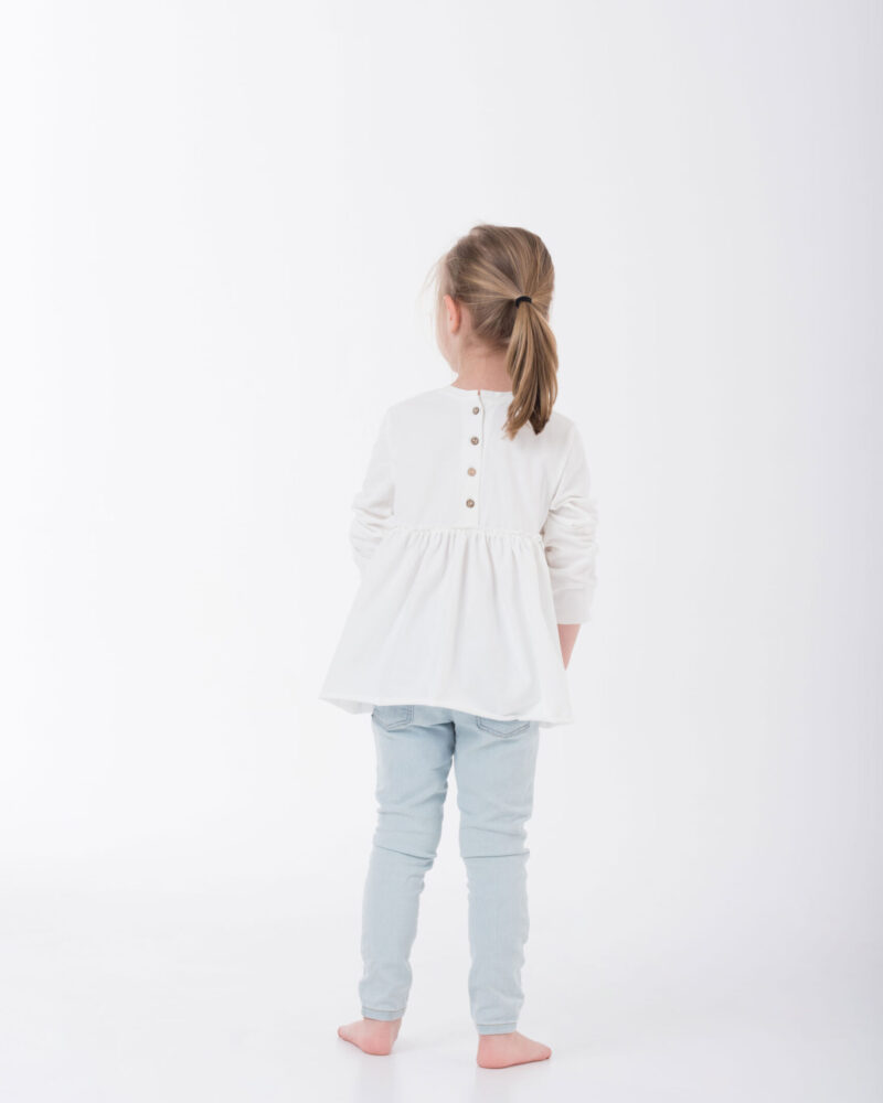 dziecko w białej bluzce z drewnianymi guzikami