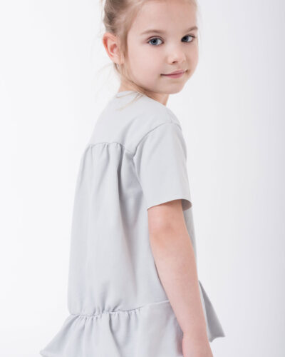 dziewczynka w bluzeczce z falbanką stojąca bokiem