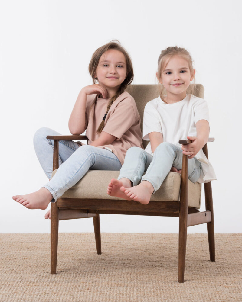 dziewczynki w jasnych t-shirtach siedzą na krześle