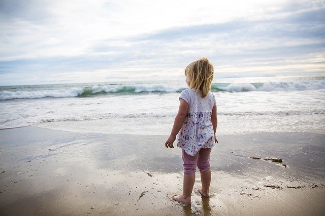 dziewczynka w bluzeczce i getrach na plaży
