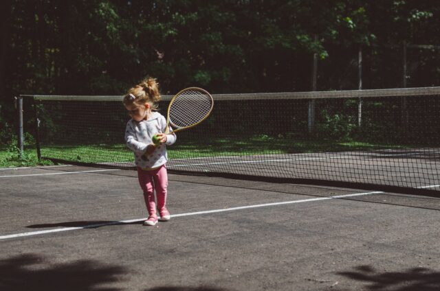 małe dziecko w bluzie i leginsach grające w tenisa